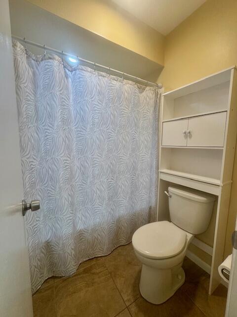 5939 Forest Hill Boulevard, Unit 205 West Palm Beach, FL 33415 - Photo 9 of 19 a white toilet sitting next to a shower curtain