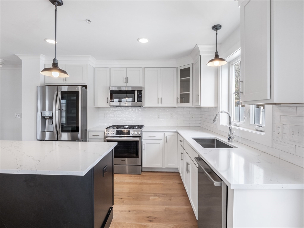 12 Hines, Unit 12 Newburyport, MA 01950 - Photo 13 of 32 a kitchen with kitchen island granite countertop a sink a stove and a wooden floors