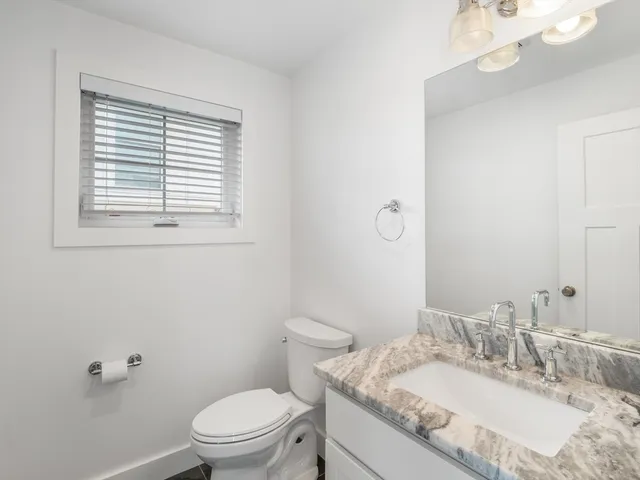 a bathroom with a granite countertop sink a toilet and a mirror