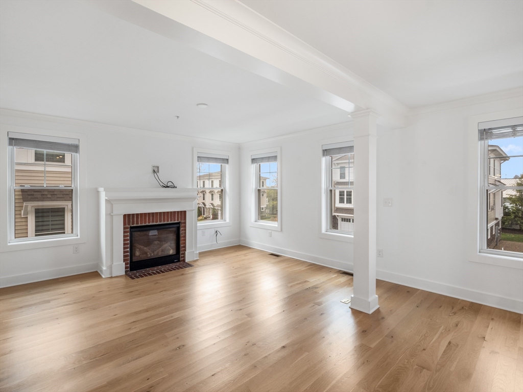 12 Hines, Unit 12 Newburyport, MA 01950 - Photo 21 of 32 an empty room with windows a fireplace and wooden floor