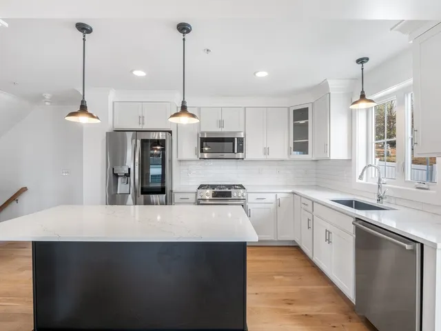 a kitchen with stainless steel appliances granite countertop a sink a stove and a wooden floors