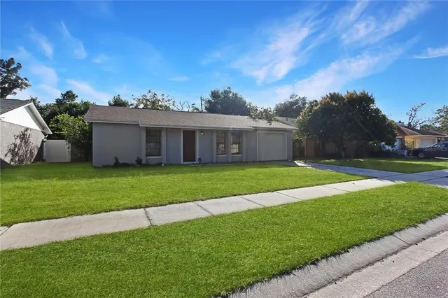a view of a house with a big yard and large trees