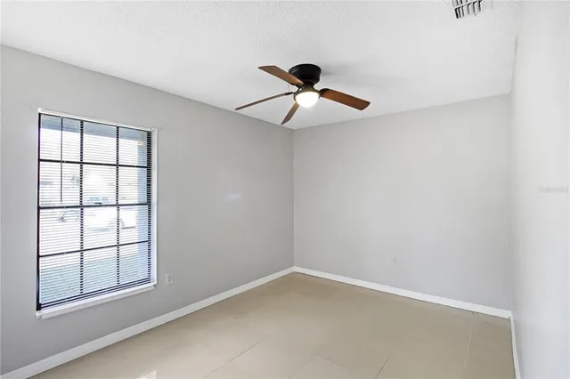 an empty room with windows and fan