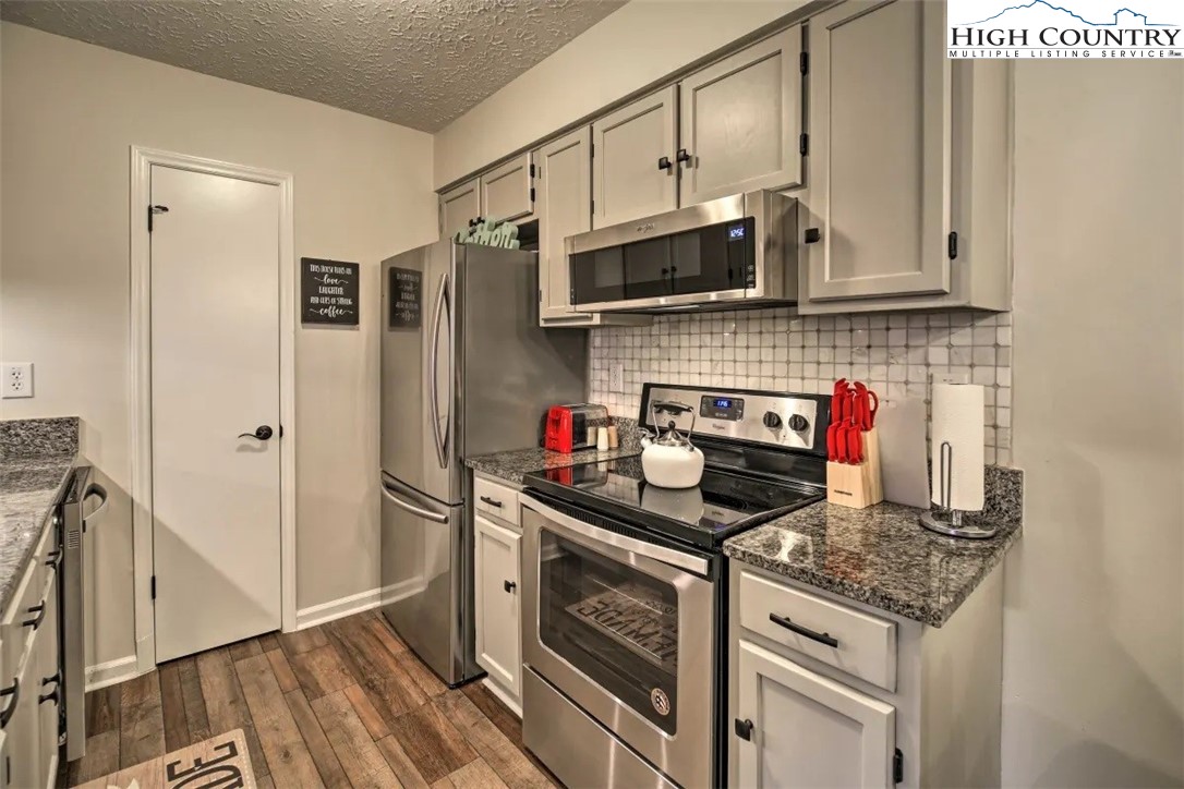 1664 Grouse Moor Drive, Unit 1 Sugar Mountain, NC 28604 - Photo 3 of 27 a kitchen with stainless steel appliances granite countertop a stove and a refrigerator