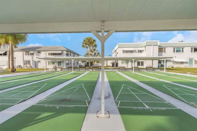 a view of a swimming pool with a lawn chairs under palm trees