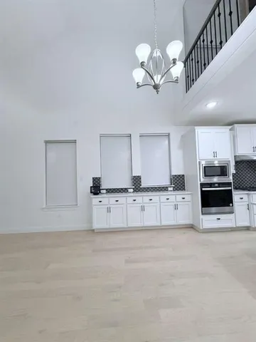 a large white kitchen with kitchen island a stove a sink a refrigerator and white cabinets