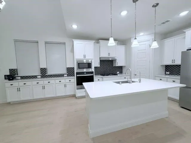 a large kitchen with kitchen island a stove a sink a center island a stove and a cabinets