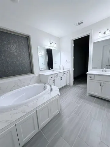 a spacious bathroom with a double vanity sink mirror and bathtub
