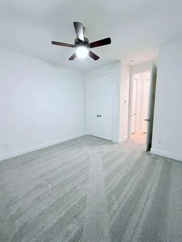 an empty room with ceiling fan and windows