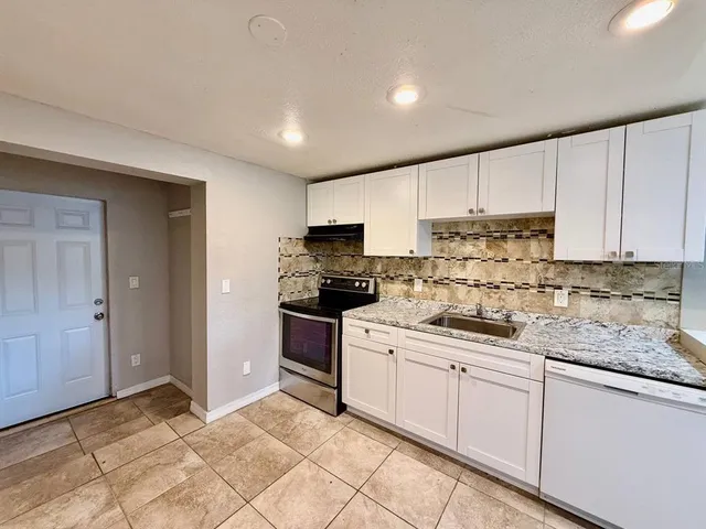a kitchen with granite countertop a sink stainless steel appliances and white cabinets
