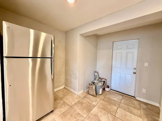a view of a refrigerator in kitchen and an empty room