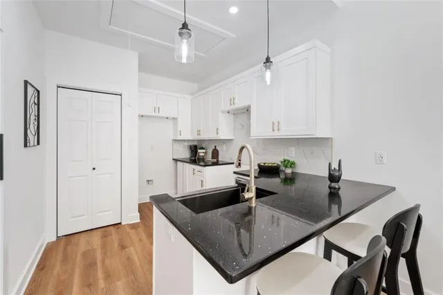a kitchen with kitchen island granite countertop a sink a stove and white cabinets