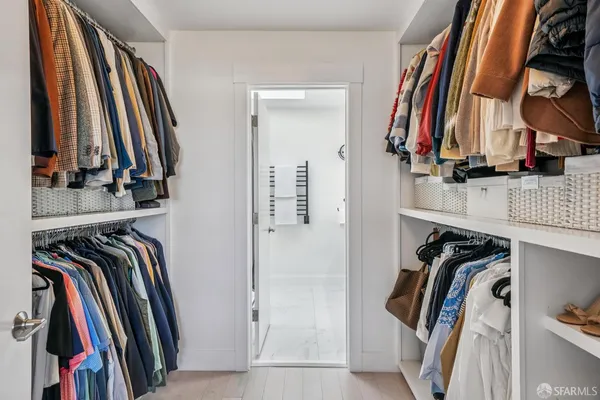 a view of walk in closet with clothes and shoes