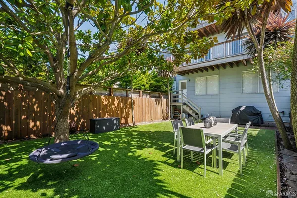 a view of a chair and table in backyard of the house