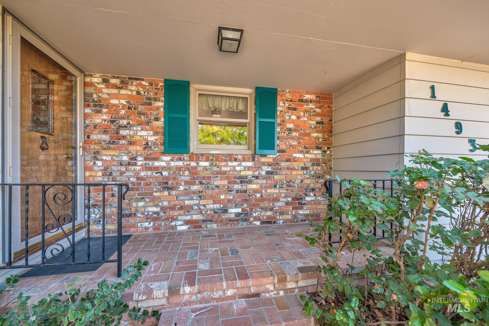 1493 Cove Road Weiser, ID 83672 - Photo 5 of 50 Brick facade with a covered entry, featuring a security screen door, decorative iron railing, and brick-patterned porch flooring