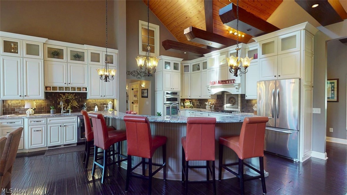 6556 Stone Road Hudson, OH 44236 - Photo 3 of 35 Gourmet kitchen with stainless steel appliances, glass tile backsplash, granite counters, miele coffee maker, convection microwave, wall oven, gas cooktop, and beverage station. Plenty of counter space, vaulted wood ceilings and beams. Designed for entertaining and family gatherings.