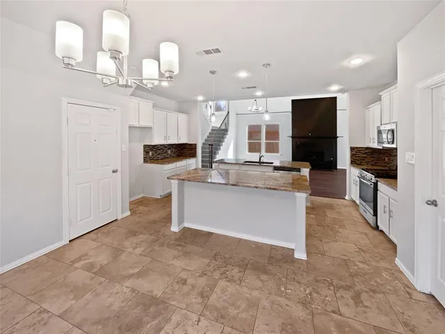 a large kitchen with granite countertop a large counter top stainless steel appliances and cabinets