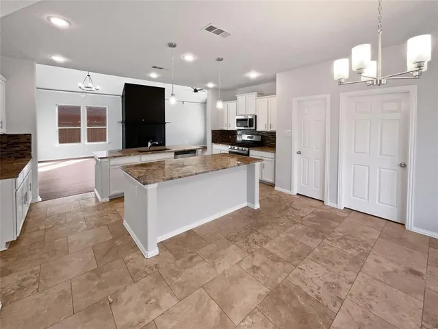 a large kitchen with a stove a sink dishwasher and a refrigerator with wooden floor