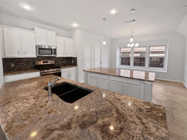 a kitchen with granite countertop a stove and a sink