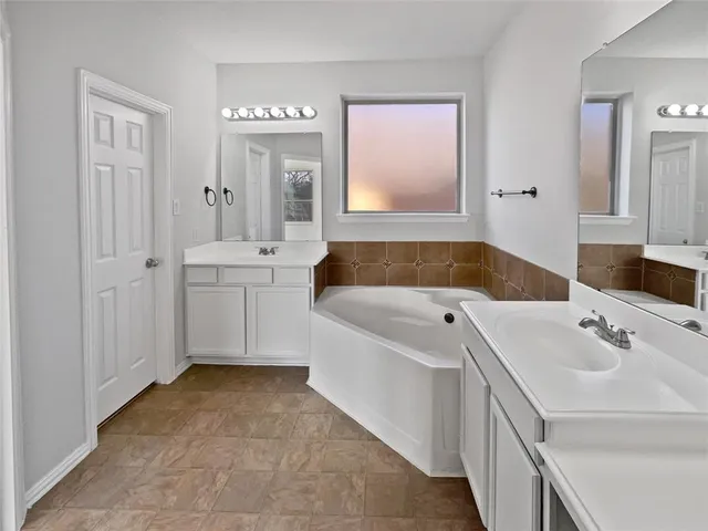 a bathroom with a tub a sink and mirror