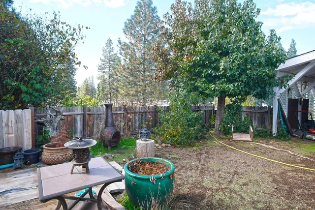 a view of a backyard with table and chairs potted plants and wooden fence