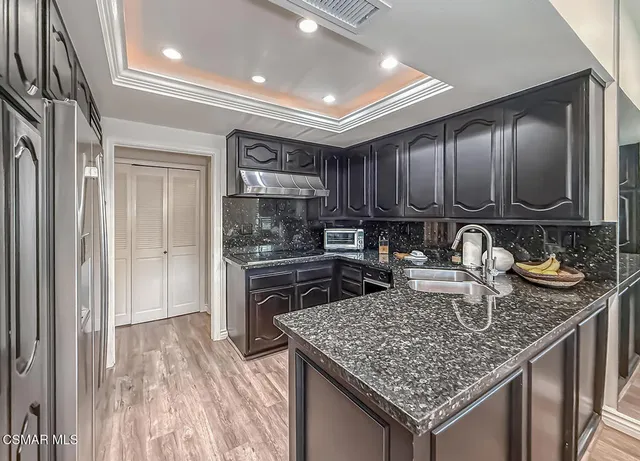 a kitchen with stainless steel appliances granite countertop a sink dishwasher stove and refrigerator with wooden floor