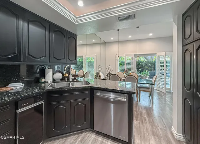 a kitchen with stainless steel appliances granite countertop a sink a stove and a wooden floors