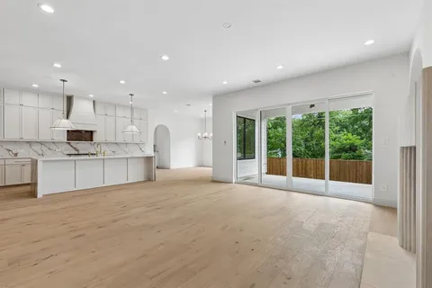 a large white kitchen with kitchen island a large window in it and a sink
