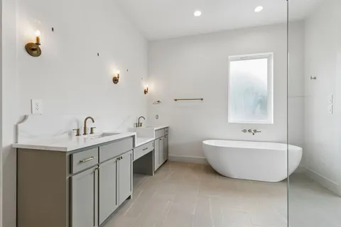 a spacious bathroom with a double vanity sink mirror and bathtub
