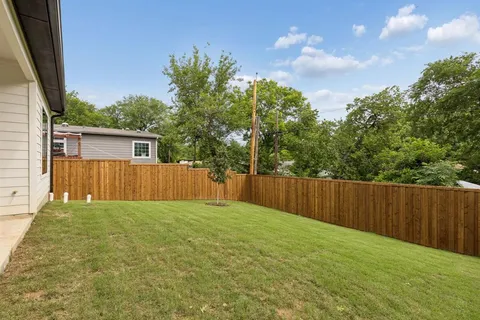 a view of backyard with small cabin and wooden fence