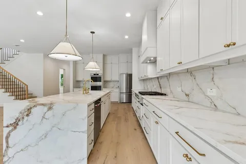 a large kitchen with stainless steel appliances granite countertop a sink a oven and a stove
