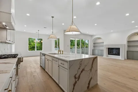 a kitchen with kitchen island granite countertop a stove a sink and a wooden floors