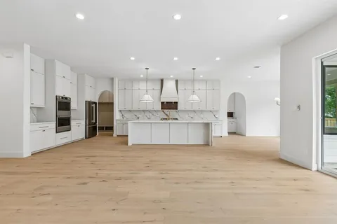 a large kitchen with stainless steel appliances kitchen island granite countertop a stove and a refrigerator