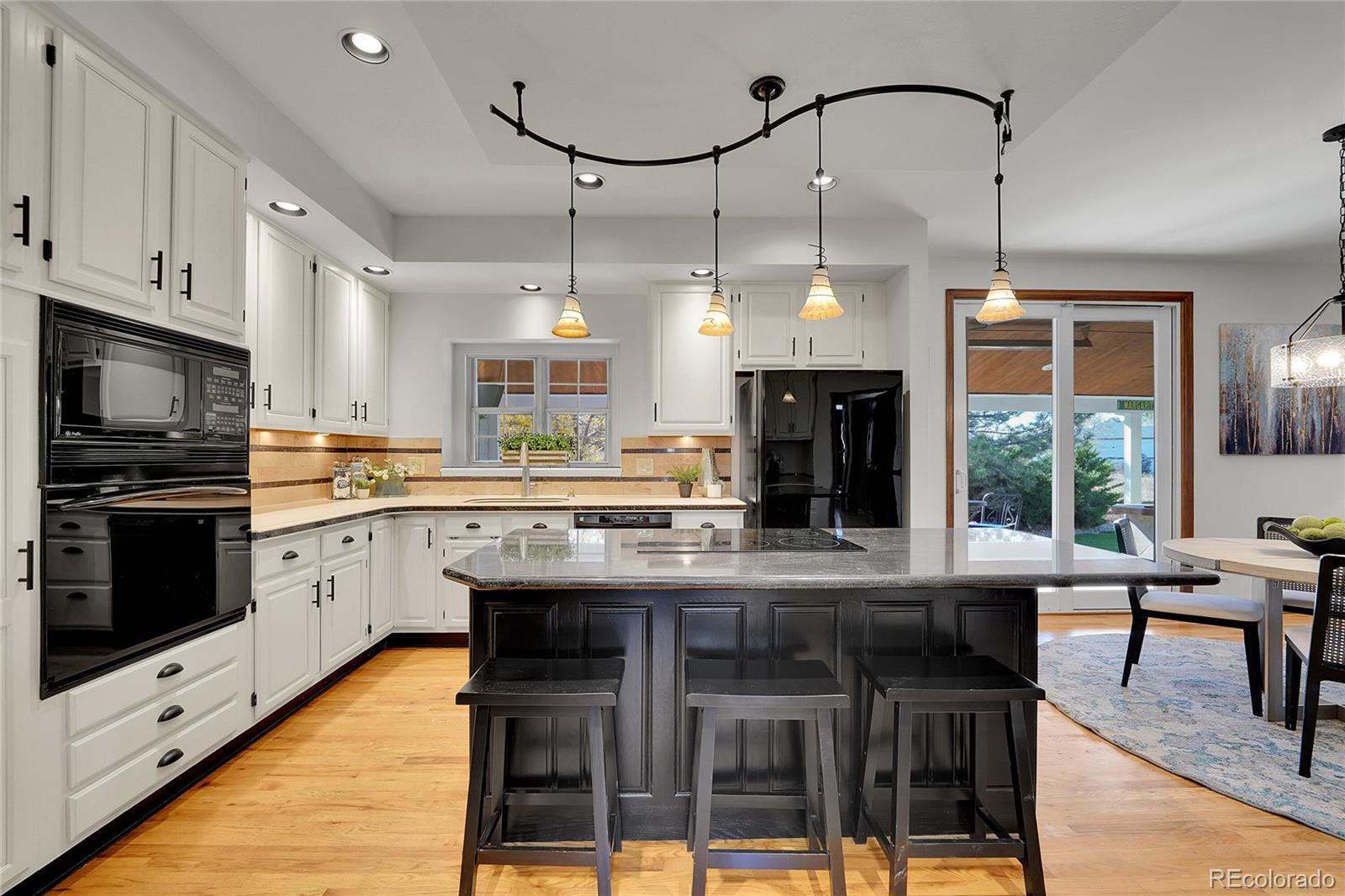 2226 Thistle Ridge Circle Highlands Ranch, CO 80126 - Photo 9 of 49 a kitchen with kitchen island granite countertop a stove a oven a dining table and chairs with wooden floor