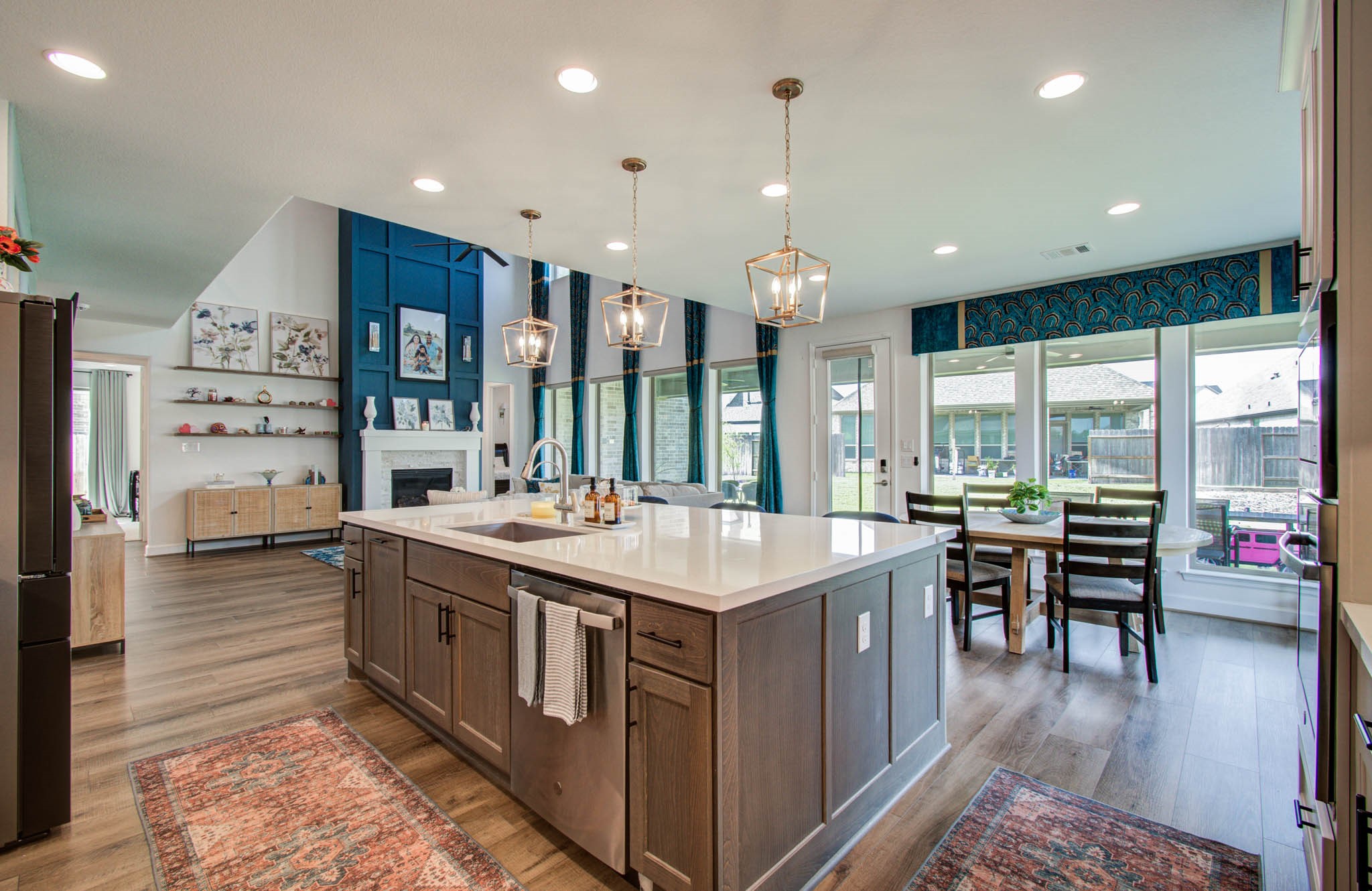 24430 Switchgrass Vly Way Katy, TX 77493 - Photo 19 of 50 The living area has a high ceiling, a bold blue accent wall with a fireplace, and large windows that provide ample natural light, with views of a fenced backyard.