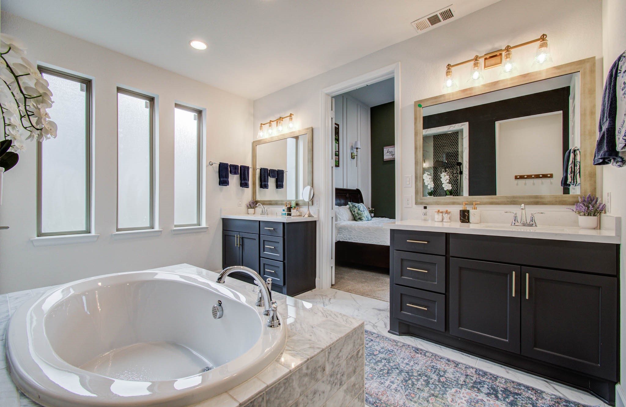 24430 Switchgrass Vly Way Katy, TX 77493 - Photo 30 of 50 This elegant bathroom features a spacious bathtub, dual vanities with dark cabinetry, and large windows for natural light. It offers a modern design with stylish fixtures, leading into a connected bedroom for convenience.