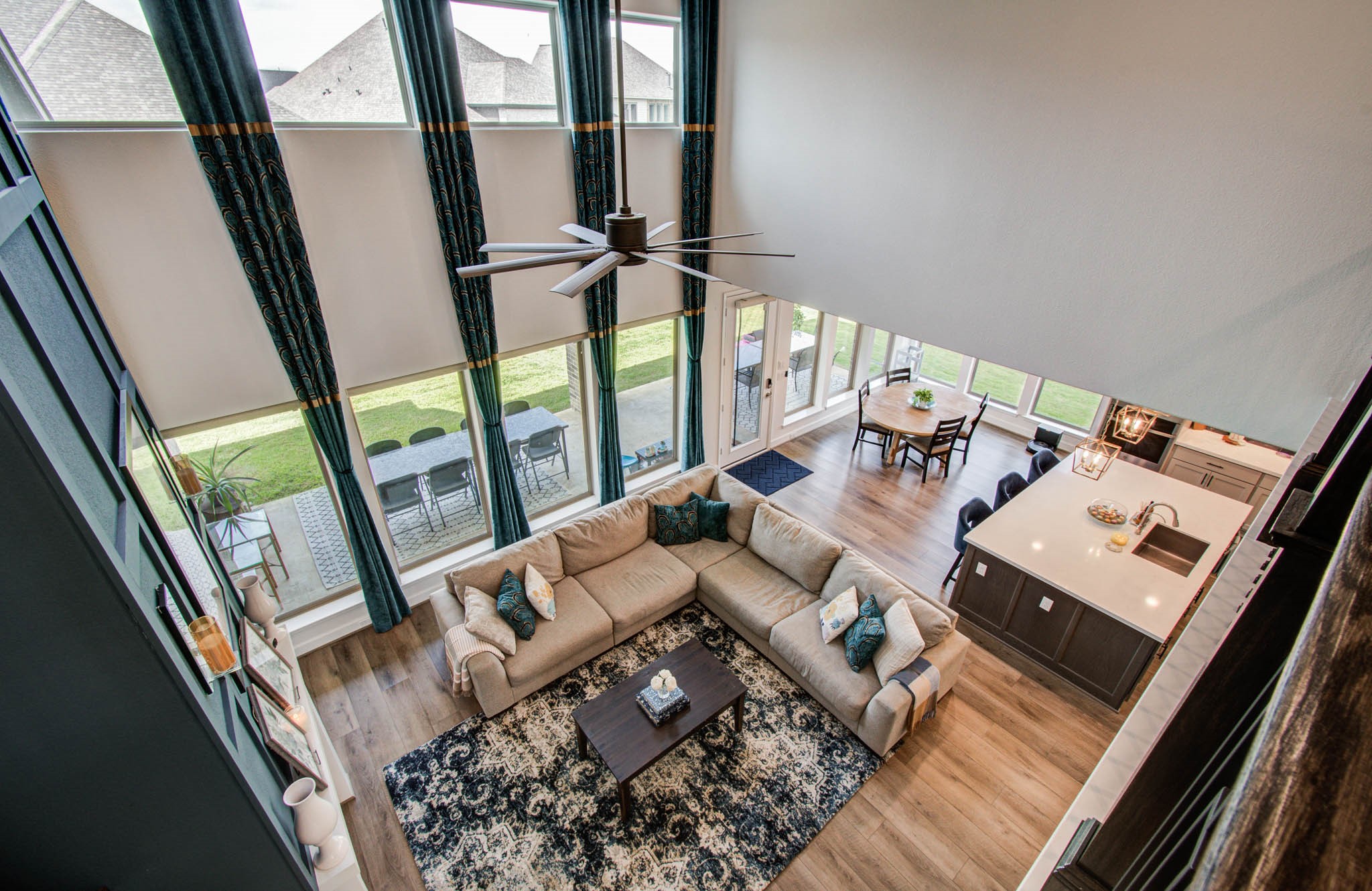 24430 Switchgrass Vly Way Katy, TX 77493 - Photo 35 of 50 This photo showcases a spacious, open-concept living area with high ceilings, and ample natural light from floor-to-ceiling windows. The area seamlessly connects to a modern kitchen with an island and dining space, creating an inviting atmosphere for family and entertaining.