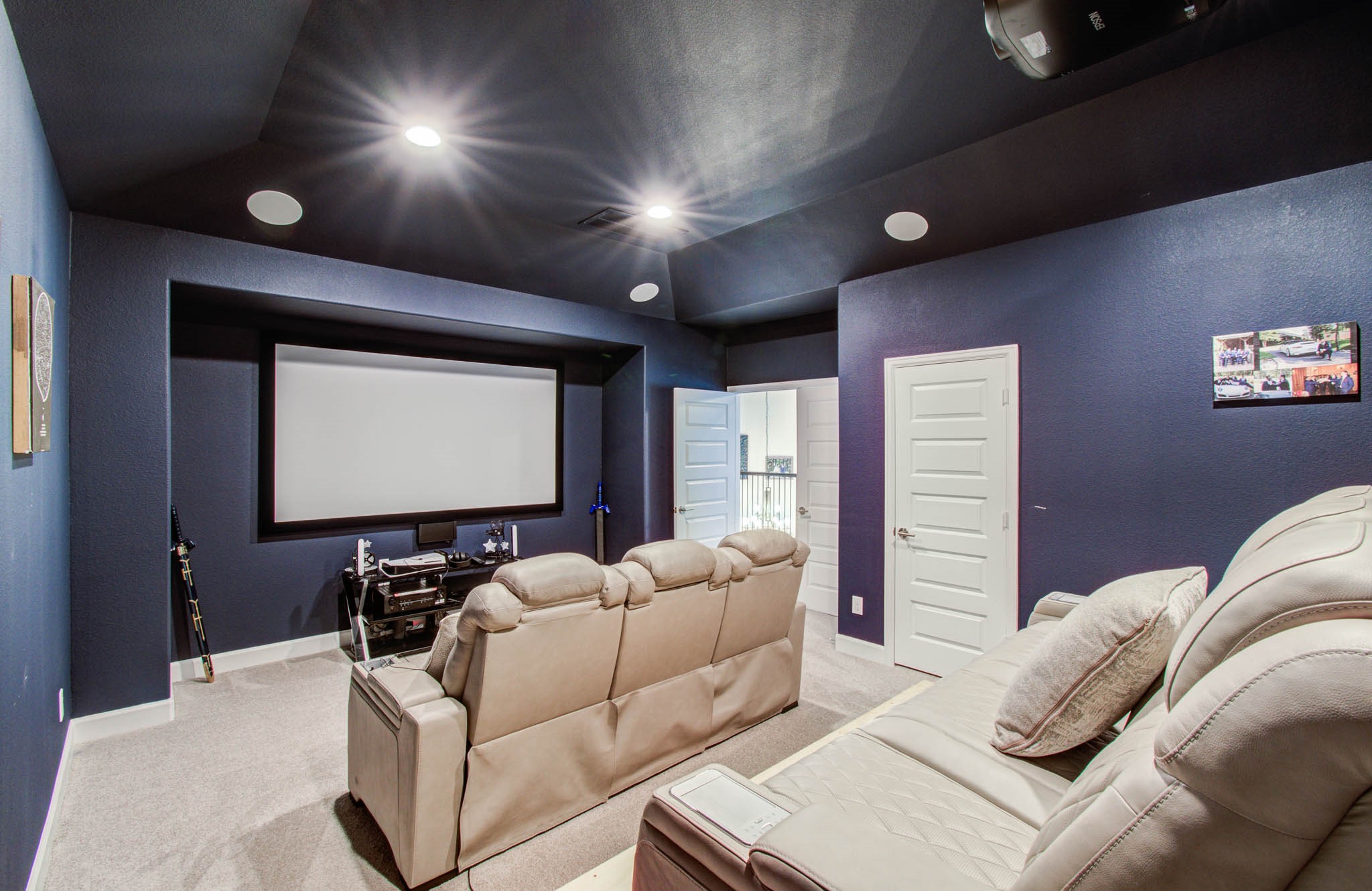 24430 Switchgrass Vly Way Katy, TX 77493 - Photo 36 of 50 This is a cozy home theater room with navy blue walls and a large screen. It features comfortable leather seating and built-in ceiling lights, creating an ideal space for movie nights. Media room was double insulated and sound proofed, along with a built-in projector and mounted screen.