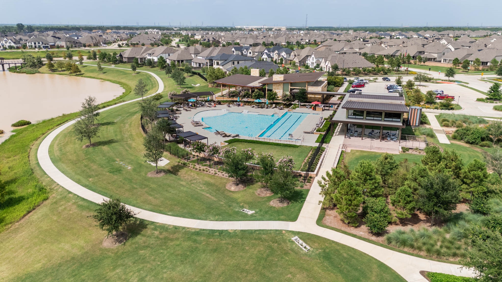 24430 Switchgrass Vly Way Katy, TX 77493 - Photo 45 of 50 This photo showcases a vibrant community with a spacious outdoor recreational area featuring a large swimming pool, green spaces, and a scenic pond. The neighborhood is composed of modern, well-maintained homes, offering a tranquil yet active lifestyle.
