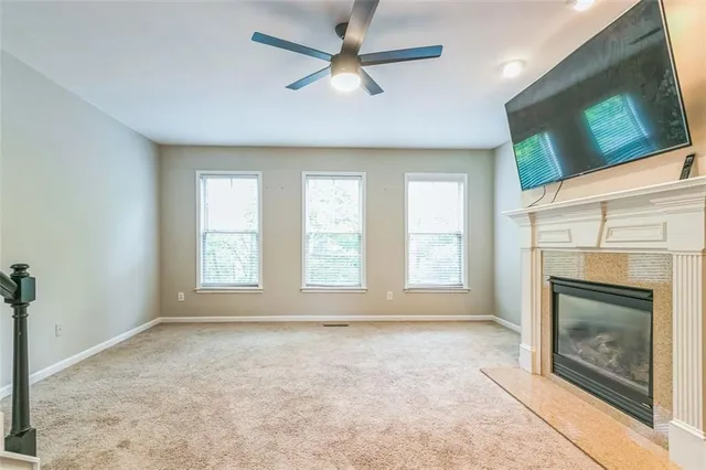 an empty room with windows fireplace and fan