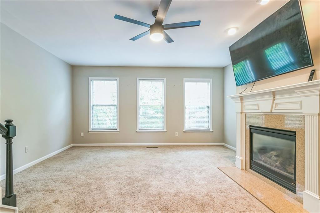 4358 Grove Field Court Northwest Suwanee, GA 30024 - Photo 12 of 17 an empty room with windows fireplace and fan