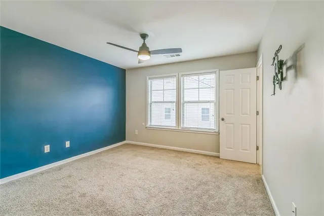 an empty room with windows and chandelier fan