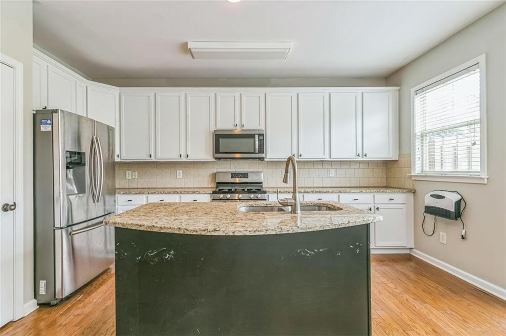 4358 Grove Field Court Northwest Suwanee, GA 30024 - Photo 8 of 17 a kitchen with granite countertop a refrigerator a sink a stove a microwave and cabinets