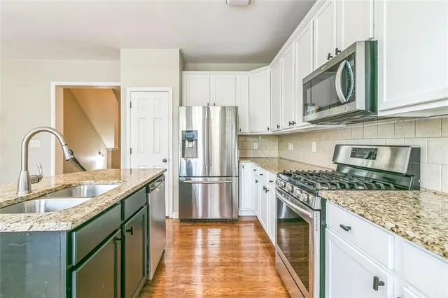 a kitchen with stainless steel appliances granite countertop a sink stove and refrigerator