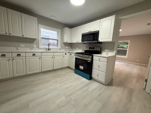 a kitchen with a sink stainless steel appliances and window