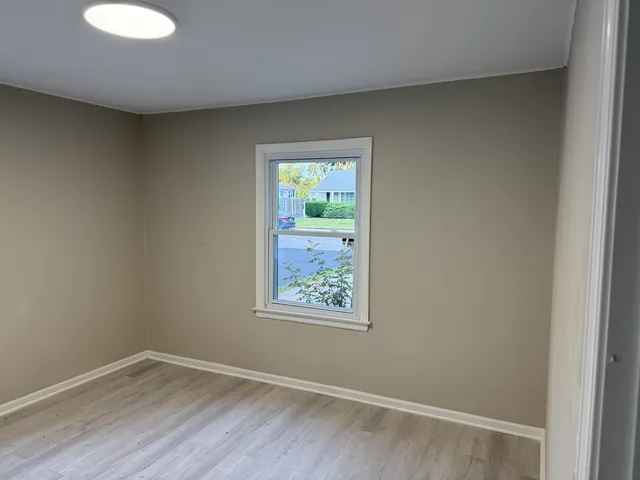 an empty room with wooden floor and a window