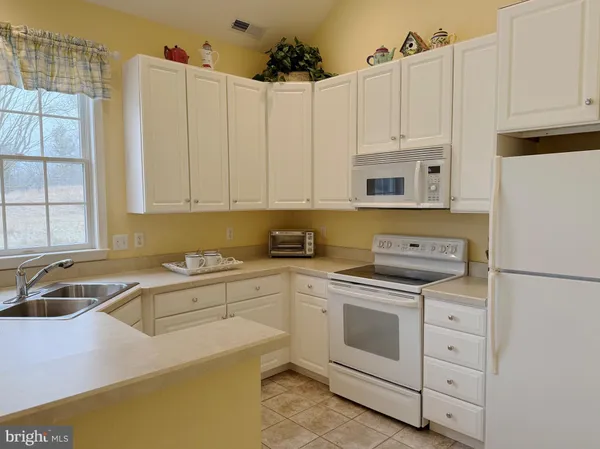 a kitchen with granite countertop white cabinets and white appliances