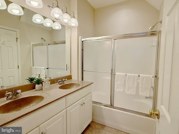 a bathroom with a sink vanity granite and a glass door shower
