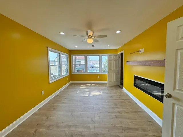 a view of an empty room with a window and a kitchen