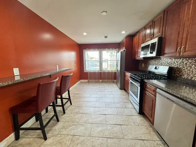 a kitchen with stainless steel appliances kitchen island granite countertop a stove a sink and a microwave